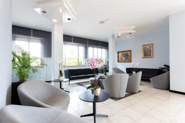 Sala d'attesa moderna con poltrone e piante.