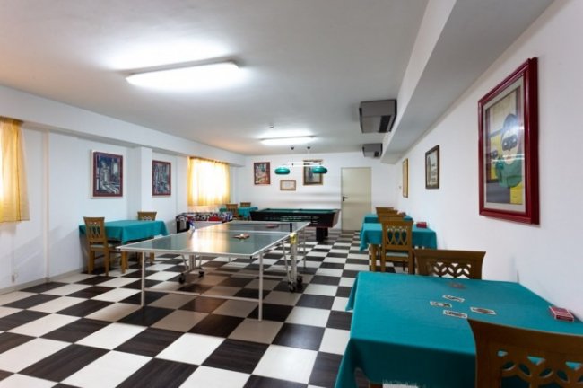 Sala giochi con tavoli e tavolo da ping pong.