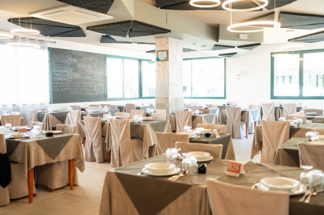 Sala da pranzo con tavoli apparecchiati.