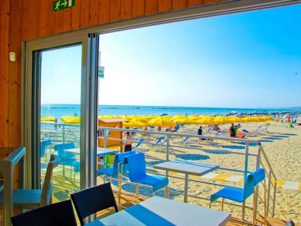 Vista dal bar sulla spiaggia con ombrelloni gialli.