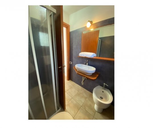 Bagno con doccia, lavabo e bidet su piastrelle beige.