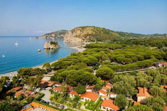Vista aerea di una spiaggia con montagne e villette.