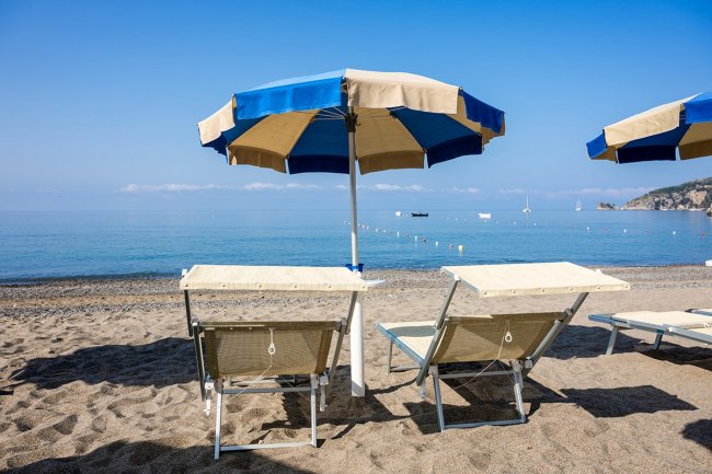 Due lettini e ombrellone blu sulla spiaggia.