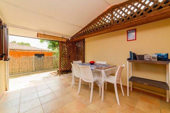 Veranda con tavolo e sedie bianche.