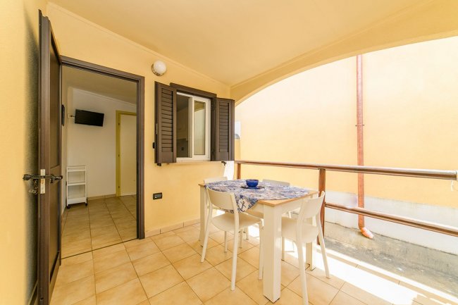 Balcone con tavolo, sedie bianche e pareti gialle.