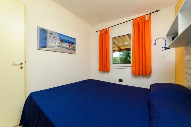 Camera con letto matrimoniale e tende arancioni.