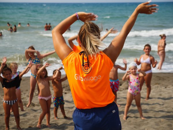 Animatrice e bambini fanno esercizi sulla spiaggia.