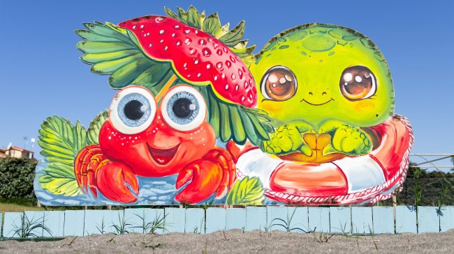 Scultura colorata di un granchio e una tartaruga sorridenti.