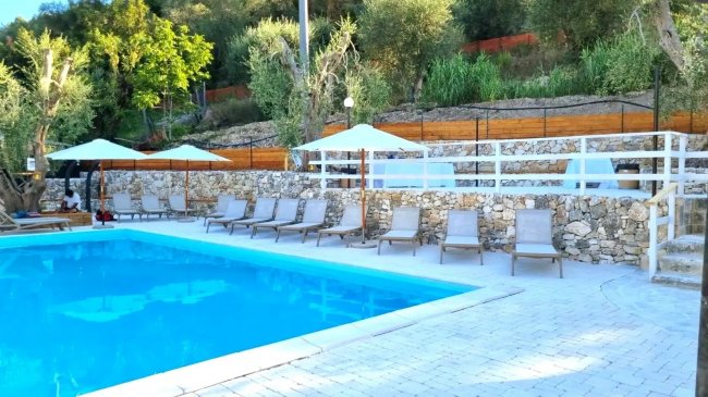 Piscina azzurra con lettini e ombrelloni bianchi.