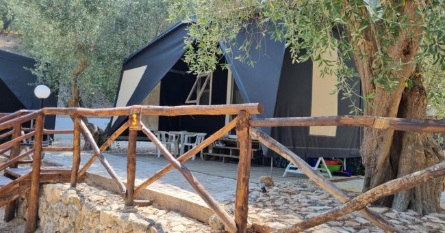 Tenda glamping tra gli alberi, con una veranda.