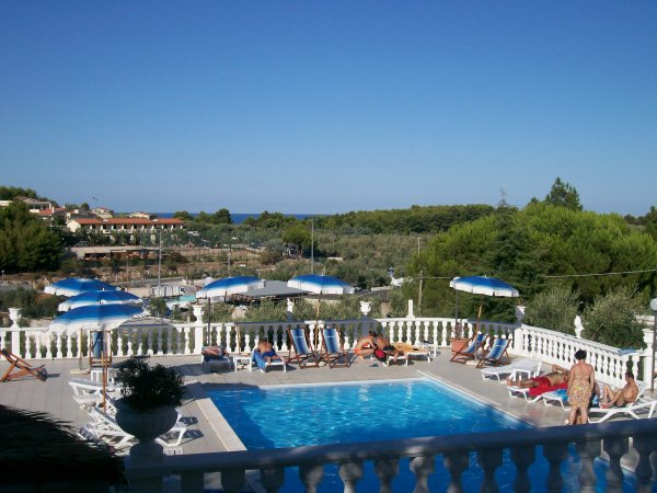 Piscina con lettini e ombrelloni blu e bianchi.
