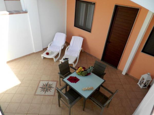 Patio con sedie a sdraio e tavolo, frutta al centro.