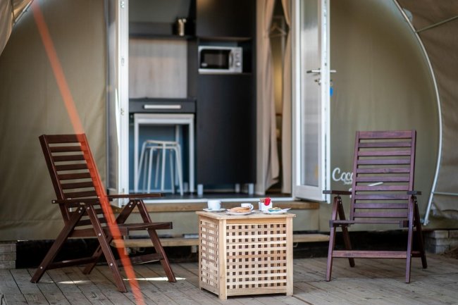 Terrazza con sedie, tavolino e interno visibile.