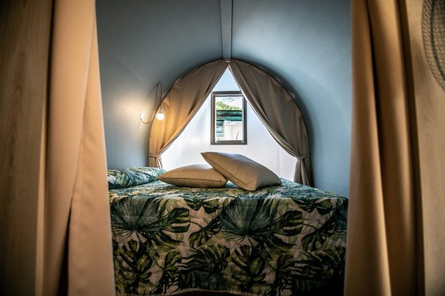 Letto matrimoniale in una tenda con finestre.