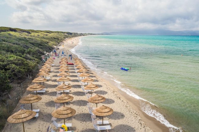 Spiaggia con ombrelloni di paglia e mare blu.