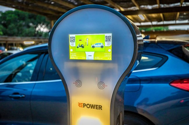 Stazione di ricarica per veicoli elettrici davanti a un'auto blu.