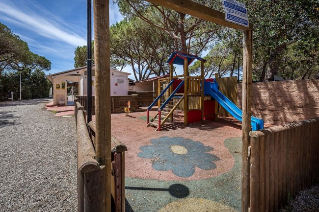 Parco giochi con scivolo e pavimento colorato.