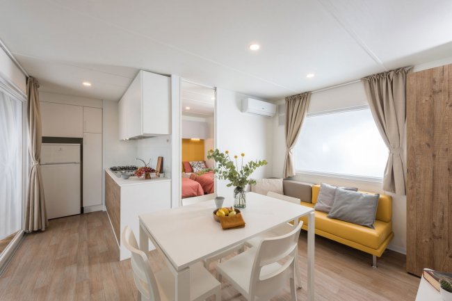 Soggiorno con tavolo bianco e divano giallo.