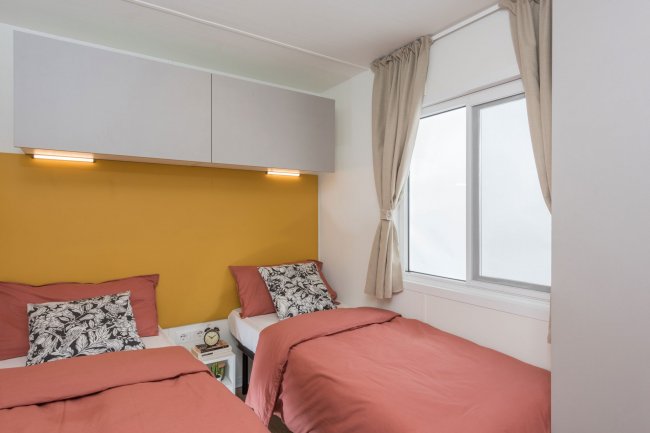 Camera con letti singoli e parete gialla.