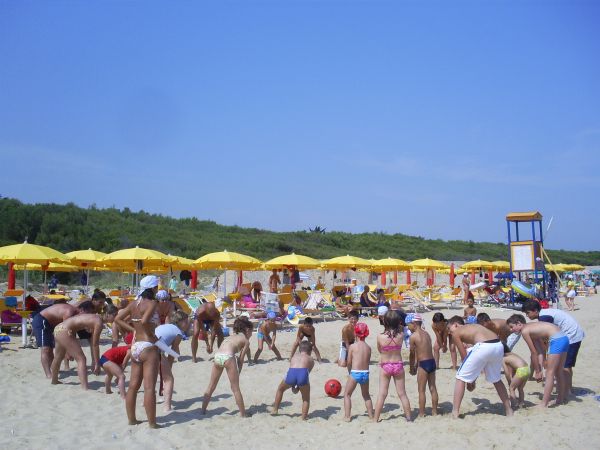 Bambini che giocano sulla spiaggia sotto ombrelloni gialli.
