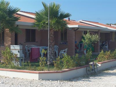 Un bungalow con tetti rossi, circondato da palme e biciclette.