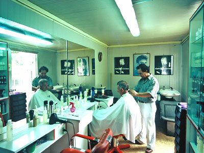 Salone di barbiere con due clienti seduti e i parrucchieri che lavorano.