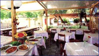 Ristorante all'aperto con tavoli apparecchiati e portate su un tavolo laterale.