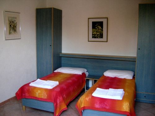 Due letti singoli con coperte colorate e armadi. Decorazioni sul muro.