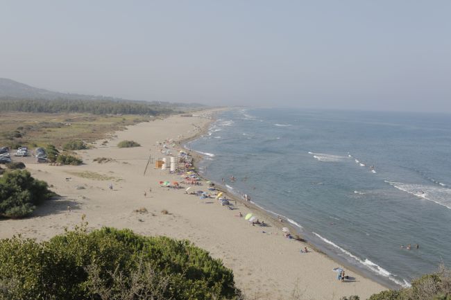 Vista aerea di lunga spiaggia sabbiosa e mare calmo.