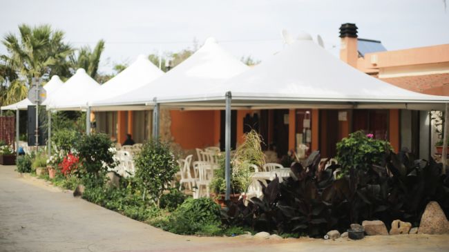 Ristorante esterno con tettoie bianche e piante.