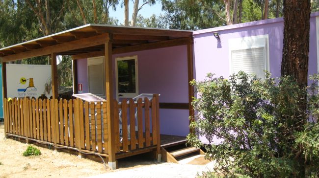 Bungalow viola con veranda e staccionata in legno.