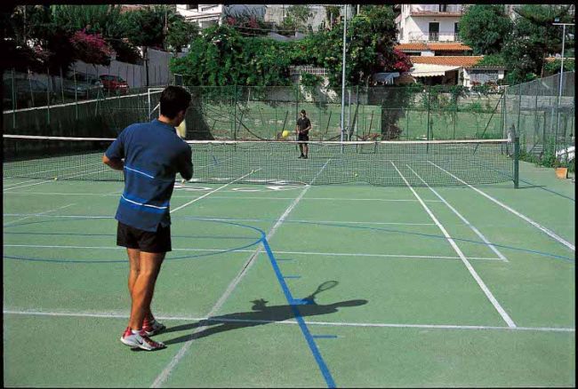 Due persone giocano a tennis su un campo all'aperto.