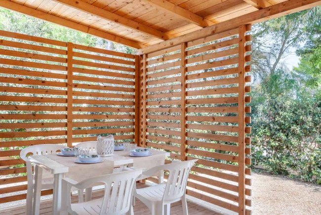 Tavolo apparecchiato sotto un gazebo in legno.