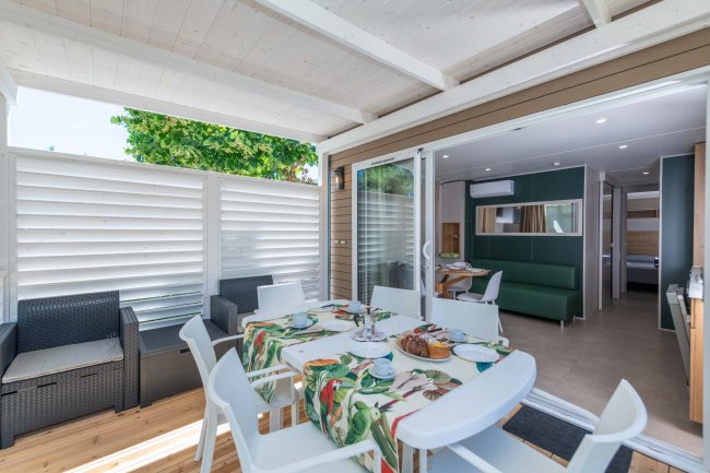 Veranda arredata con tavolo, sedie e divano.