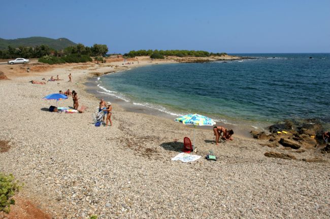 Una spiaggia di ciottoli con persone e ombrelloni vicino al mare.