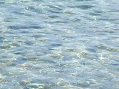 Superficie del mare con acqua trasparente e increspature.