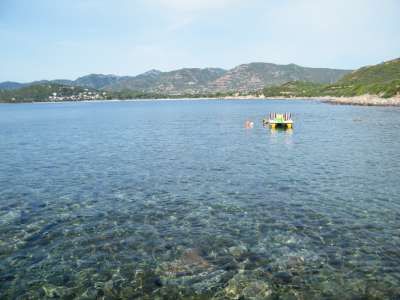 Mare limpido con una zattera e colline sullo sfondo.