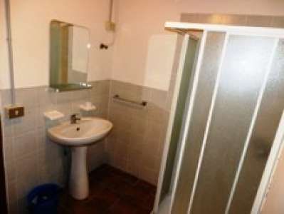 Un bagno con doccia, specchio rettangolare e lavandino bianco.
