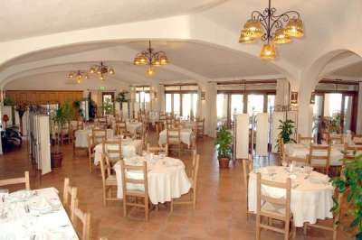 Un ristorante con tavoli apparecchiati, sedie in legno e lampade sospese.
