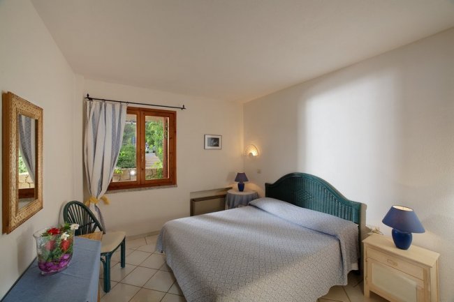 Camera da letto semplice con finestra e letto matrimoniale.