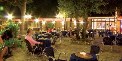 Persone sedute all'aperto in un caffè illuminato di notte.