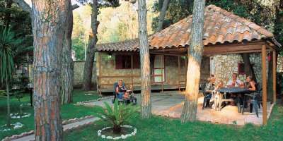 Una casa di pietra con patio coperto, persone sedute a un tavolo nel giardino.