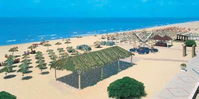 Una spiaggia sabbiosa con ombrelloni di paglia e un cielo limpido.