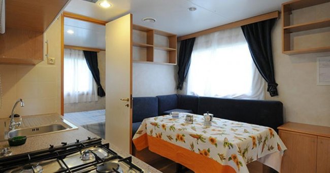 Cucina in roulotte con tavolo apparecchiato e divano.