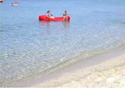 Due persone in canoa rossa sul mare calmo vicino alla riva.