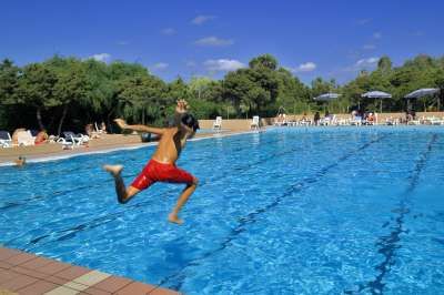 Persona in costume rosso mentre salta in una piscina azzurra.