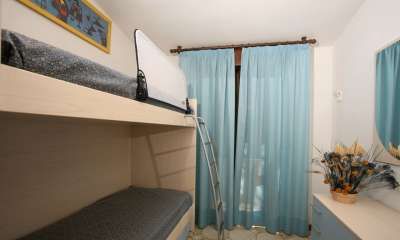 Camera con letto a castello, tenda blu e decorazioni sul tavolo.