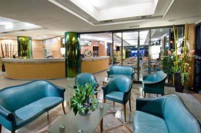 Area lounge con poltrone blu, piante decorative e un banco bar sullo sfondo.