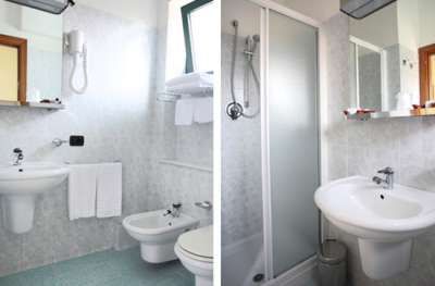 Bagno con lavabo, bidet, WC e doccia. Arredamento bianco e chiaro.