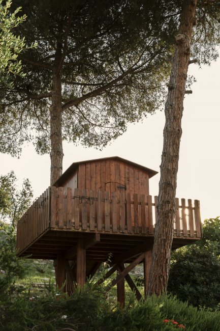 Casetta su piattaforma in legno tra gli alberi.